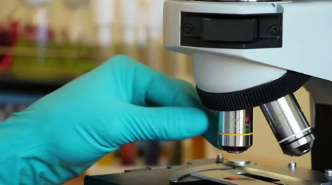 A man turns objectives of microscope on the moving background Stock Footage 63045642