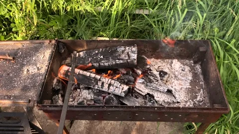 A man turns over burning coals for BBQ in a barbecue in nature. Stock Footage 196889342