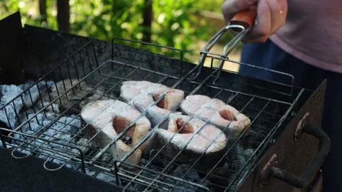 Man turns over the grill with salmon stakes. Summer barbecue, cookout Stock Footage 340333049