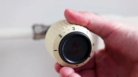 A man turns the thermostat down to reduce heating bills during energy crises. Stock Footage 235558022
