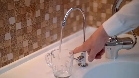 A man turns on the water on a second shiny chrome faucet of clean drinking water Video stock 303173984