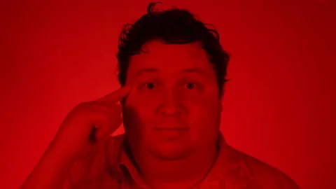 Man twisting finger at a temple judging you crazy. Red lighting Stock Footage 123173682