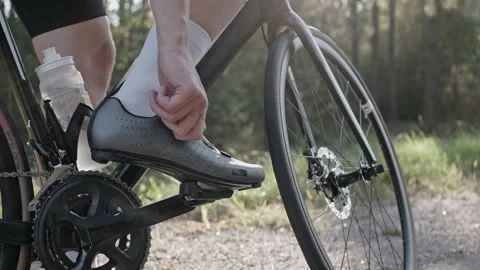 Man twists the contact bicycle shoes on a road bike at the sunset in the woods Vídeo Stock 166172753