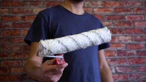 A man twists a paint roller in his hand 4K Stock Footage 150287604