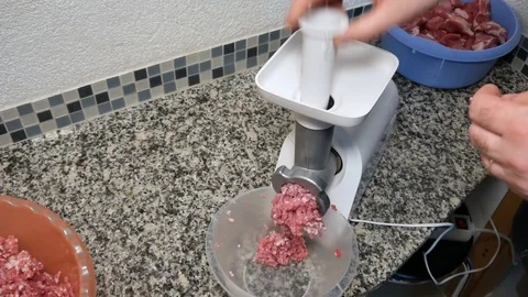 A man twists pork meat in an electric meat grinder Vídeos de archivo 101201760