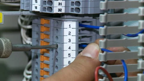 Man twists screw on switch board with blue wires Vídeo Stock 90604948