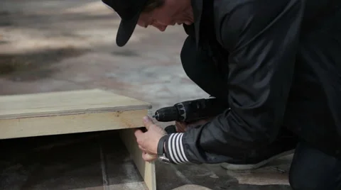 Man twists the screws on the wooden structure in the skatepark Stock Footage 59242560