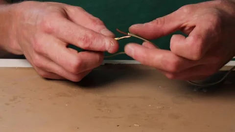 Man twists two stripped wires together and prepares to slide a heat shrink .. Stock Footage 318674569