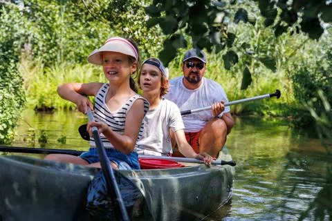 Man with two children enjoy having fun paddling canoe rent across lake river Foto stock