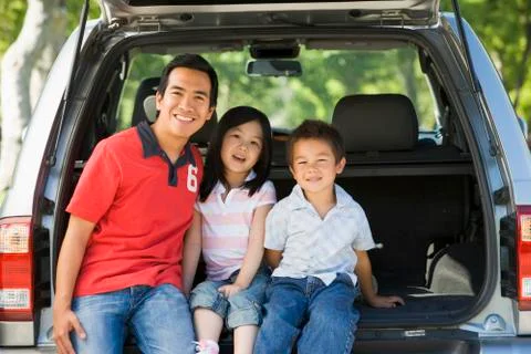 Man with two children sitting in back of van smiling Stock Photos