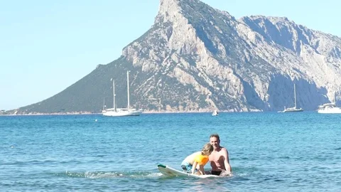 A man with two kids having fun on a paddle in the sea with a beautiful landsc Vídeos de archivo 78467350