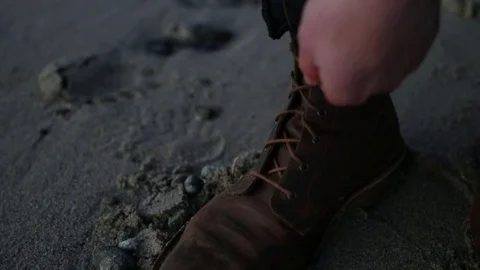 Man Tying His Boots on Beach Stock Footage 73304408