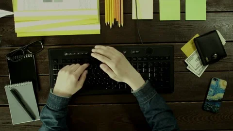 A man types on a computer keyboard on his desk and hiding something that prints Stock Footage 82008325
