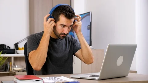Man types fast on computer keyboard then puts headphones on his head Stock Footage 95312940