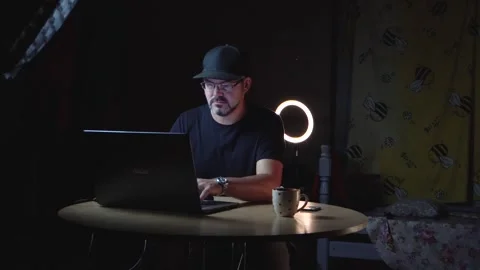 A man types on a laptop in a dark room 4K Stock Footage 320867686