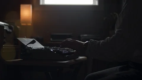 Man types on an old vintage typewriter in a moody office Stock Footage 97859468