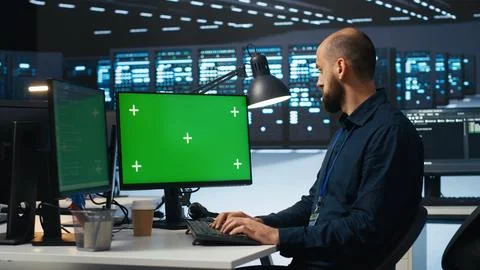 Man typing code on green screen computer in high tech data center Stock Photos