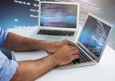 Man typing coding text on two laptops Stock Photos