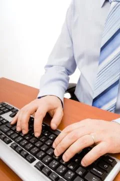 Man typing in the computer keyboard and using a mouse. Stock Photos