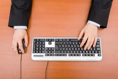 Man typing in the computer keyboard and using a mouse. Stock Photos