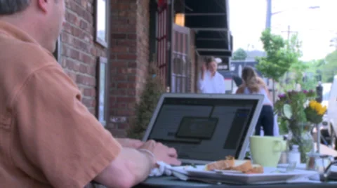 Man typing on his laptop at a sidewalk cafe Stock Footage 32302353