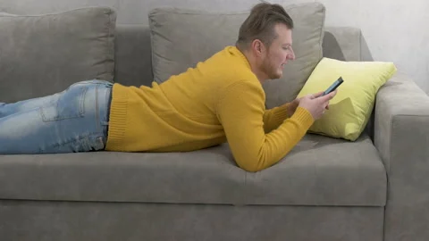 A man is typing on his smartphone, a young guy communicates with friends Stock Footage 145338336