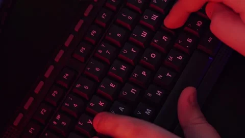 A man is typing on the keyboard, and the light around him is colored neon Stock Footage 132537772