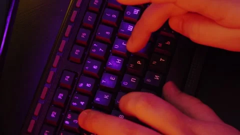 A man is typing on the keyboard, and the light around him is colored neon Stock Footage 132537803