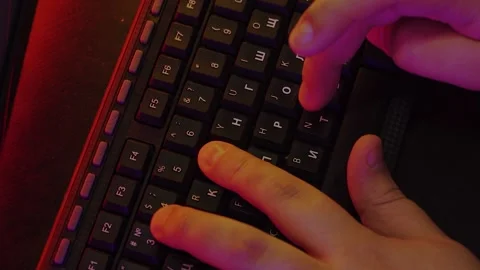 A man is typing on the keyboard, and the light around him is colored neon Stock Footage 132537829