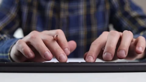 A man is typing on a keyboard and writing with a pencil while sitting at a table Stock-Footage 244599174