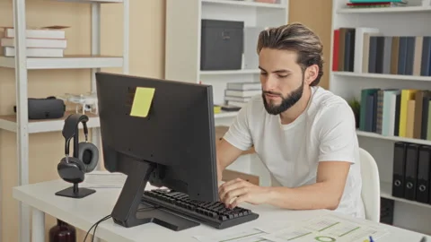 Man typing on keyboard at desktop computer in studio with headset, papers a.. Stock Footage 337371900