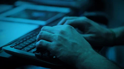 Man typing on keyboard in dimly lit, blue room Stock Footage 118976667