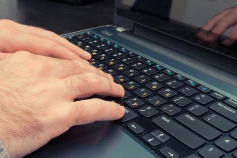 Man typing on a keyboard with letters in Hebrew and English Stock Photos