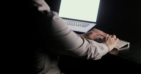 Man is typing on the keyboard looking at laptop screen sitting at the table on Stock Footage 105302663