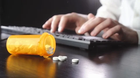 Man is typing on a keyboard. Pills in the foreground Stock Footage 118446400
