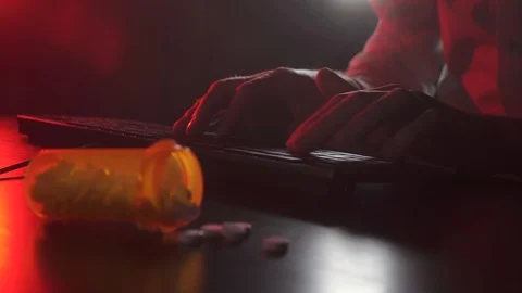 Man is typing on a keyboard. Pills in the foreground Vídeos de archivo 118446775