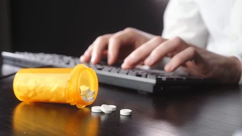Man is typing on a keyboard. Pills in the foreground Stock Footage 118935566