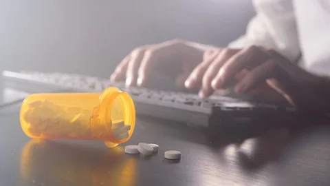 Man is typing on a keyboard. Pills in the foreground Stock Footage 120082211