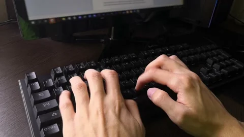 A man is typing on a keyboard while sitting at a computer Stock Footage 160555562