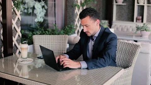 Man typing on laptop and drinking coffee Stock Footage