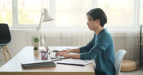 Man typing on laptop and making notes Stock Footage 145294577