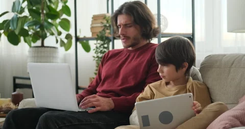 Man typing on laptop and son using digital tablet Video stock 145227734
