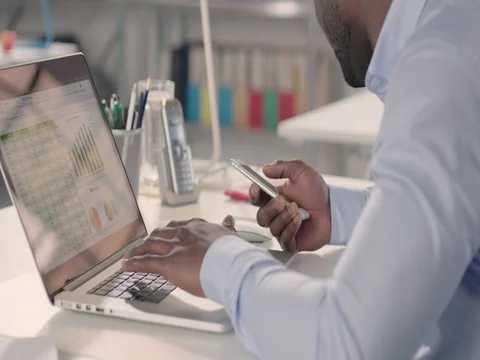 Man typing on laptop and using phone in a startup office - track left. Stock Footage 72825398