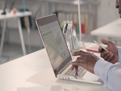 Man typing on laptop and using phone in a startup office - track right. Stock Footage 72825577