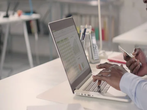 Man typing on laptop and using phone in a startup office - track right. Stock Footage 72826063