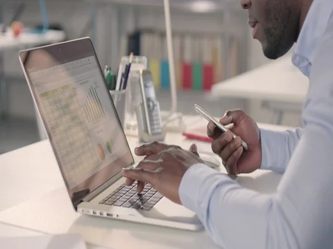 Man typing on laptop and using phone in a startup office - track left. Stock Footage 72826261