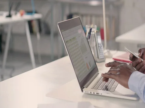 Man typing on laptop and using phone in a startup office - track right. Stock Footage 72826424