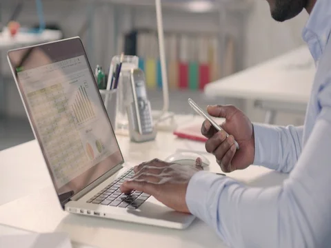 Man typing on laptop and using phone in a startup office. Stock Footage 72831574