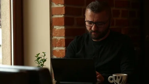 Man typing on laptop and using smartphone while sitting in the cafe Stock Footage 80423761