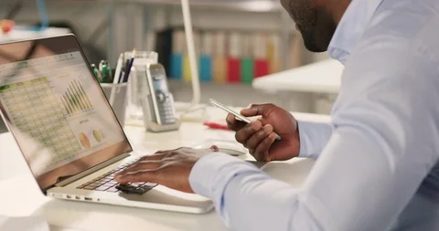 Man typing on laptop and using phone in a startup office. Stock Footage 92165855